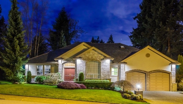 Image of the exterior of a home with its lights turned on all around the house.