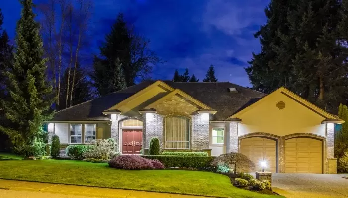 Image of the exterior of a home with its lights turned on all around the house.