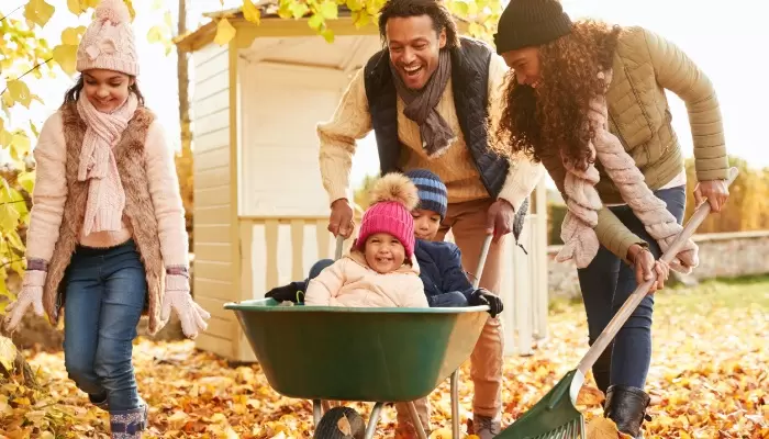 parents in fall giving children a ride in wheelbarrow